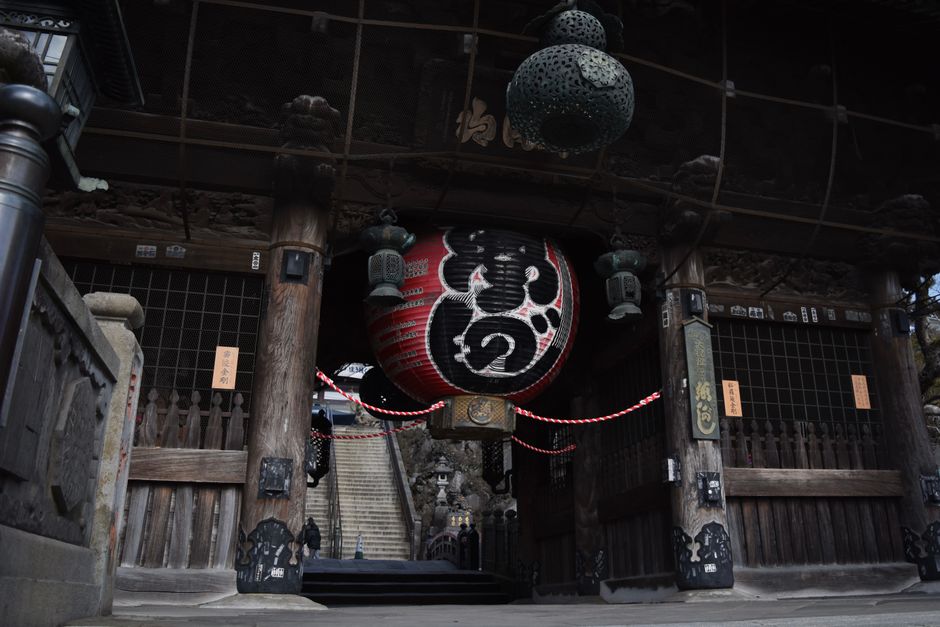 A close view of a traditional Japanese temple entrance featuring ornate lanterns and wooden architecture.