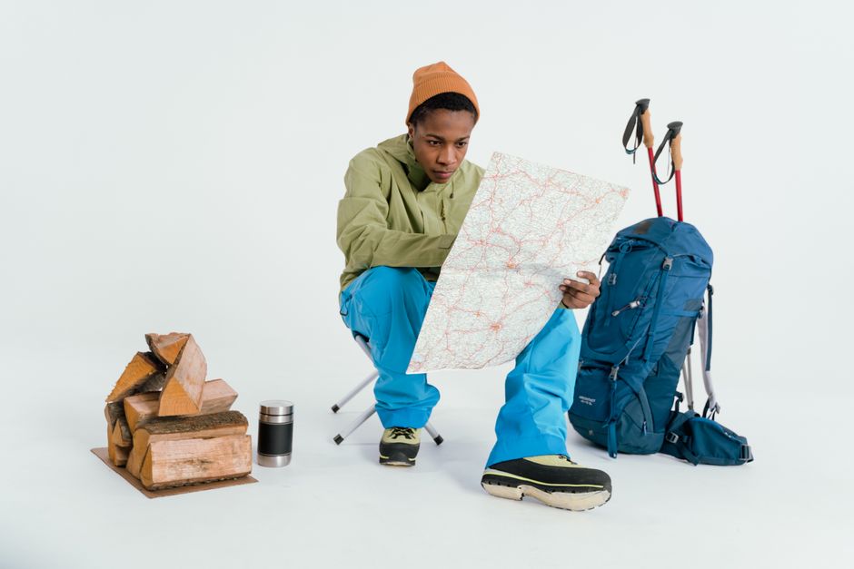 Black man preparing for winter hiking adventure with map and gear setup.